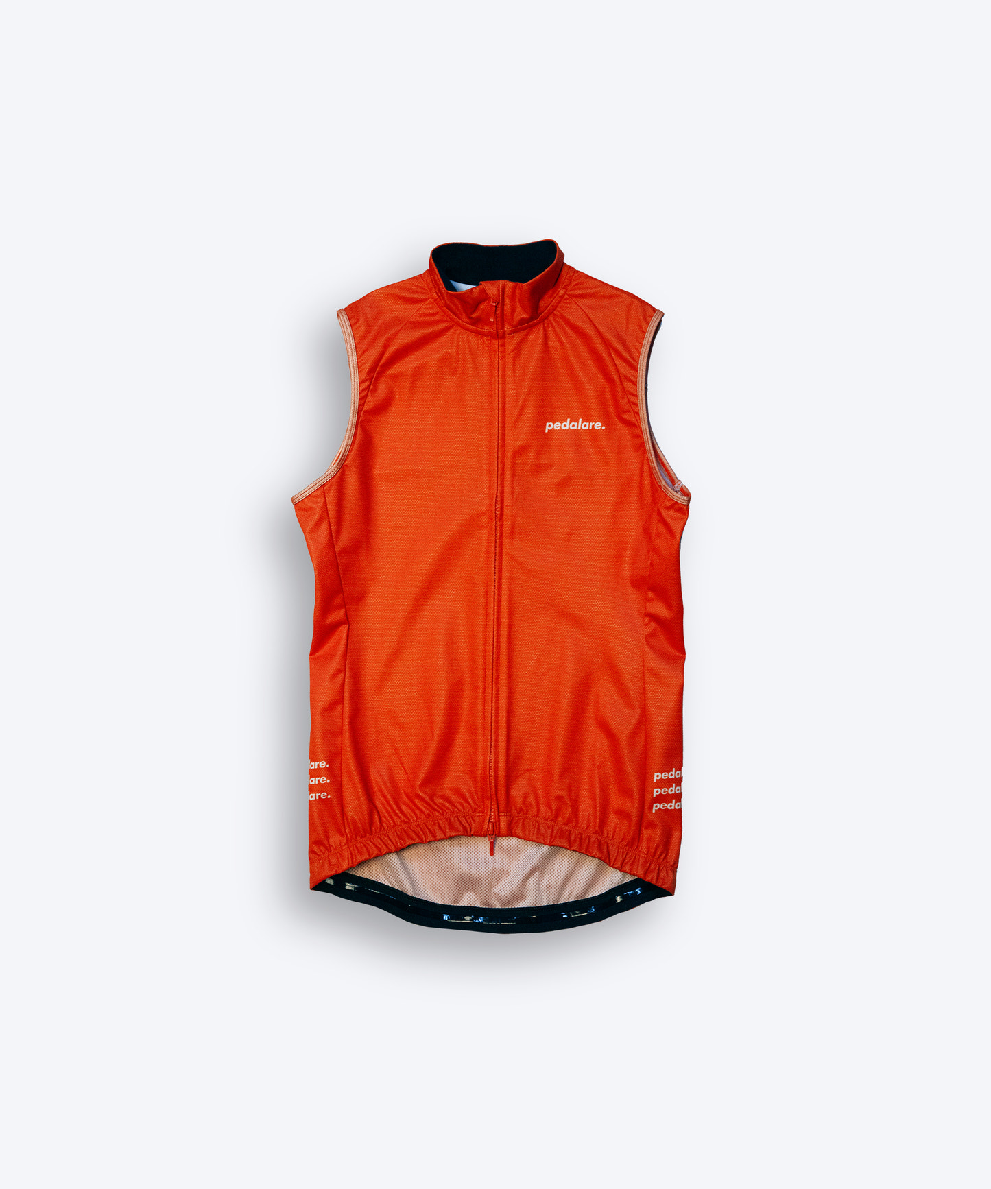 Male cyclist wearing Pedalare’s high-performance orange cycling vest, layered over a navy long sleeve jersey and black bib shorts. Side profile studio shot showcasing the vest’s aerodynamic fit and premium detailing. Lightweight, windproof men’s cycling vest ideal for cool weather rides. Designed by Perth cycling brand Pedalare for performance, comfort, and style. Aero cycling gear for dedicated road cyclists.