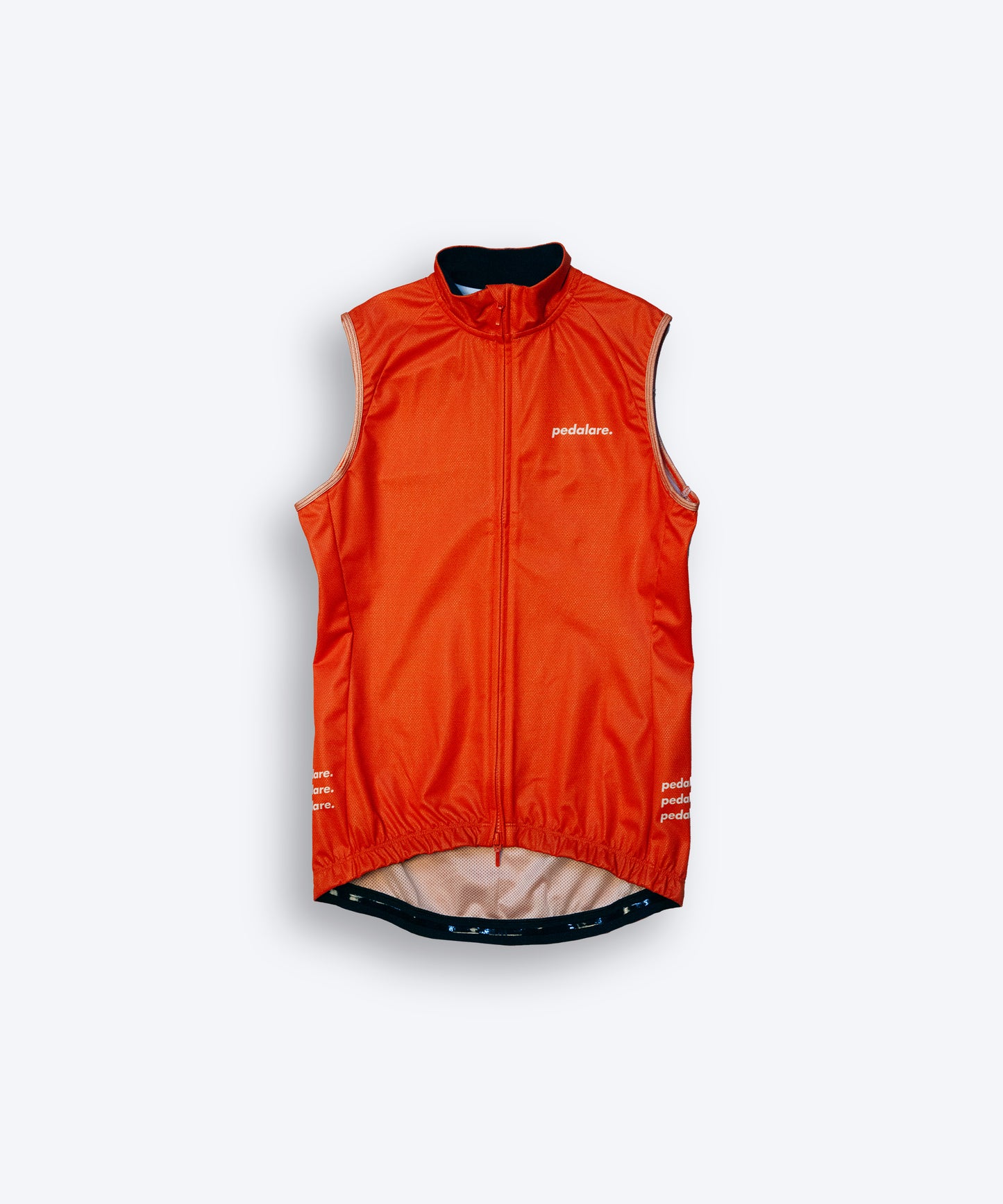 Male cyclist wearing Pedalare’s high-performance orange cycling vest, layered over a navy long sleeve jersey and black bib shorts. Side profile studio shot showcasing the vest’s aerodynamic fit and premium detailing. Lightweight, windproof men’s cycling vest ideal for cool weather rides. Designed by Perth cycling brand Pedalare for performance, comfort, and style. Aero cycling gear for dedicated road cyclists.