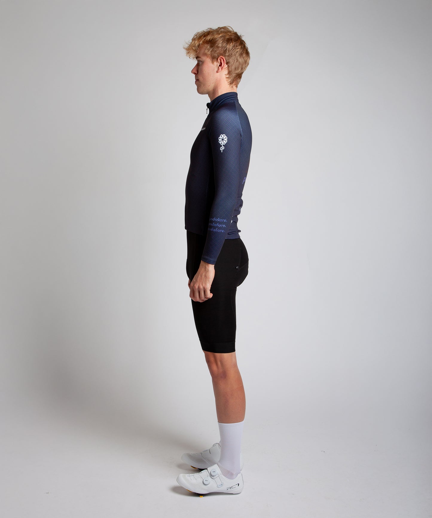 Male cyclist modelling Pedalare’s navy winter long sleeve cycling jersey, paired with black bib shorts. Side profile studio shot highlighting the jersey’s thermal fabric, streamlined fit, and subtle branding. Designed by Perth cycling brand Pedalare for cool-weather performance and style. Men’s winter cycling jersey ideal for road cyclists seeking aero cycling gear and premium cycling apparel.