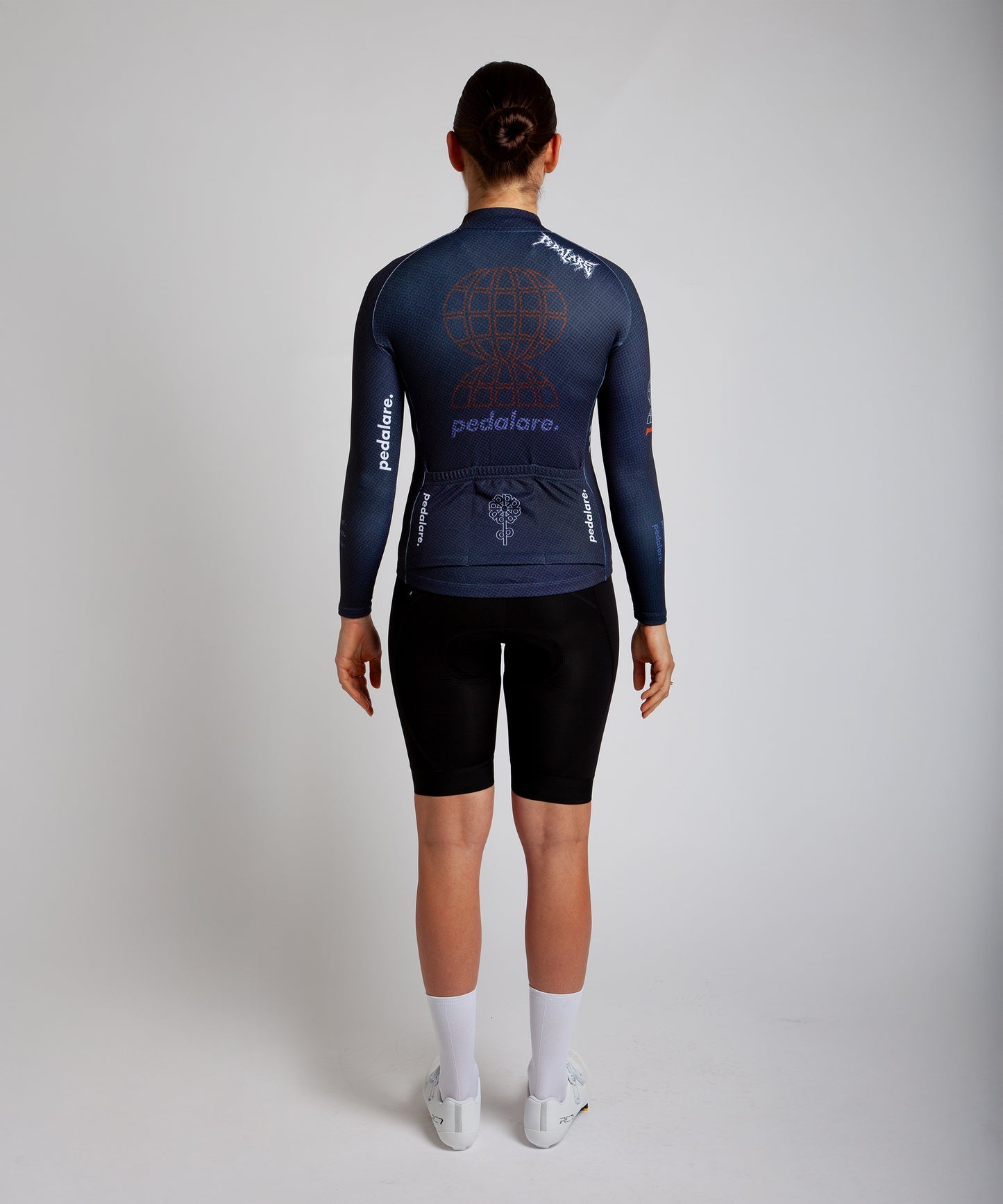 Female cyclist modelling Pedalare’s navy blue winter long sleeve cycling jersey, paired with black bib shorts. Side profile studio shot highlighting the jersey’s thermal fabric, streamlined fit, and subtle branding. Designed by Perth cycling brand Pedalare for cool-weather performance and style. Men’s winter cycling jersey ideal for road cyclists seeking aero cycling gear and premium cycling apparel.