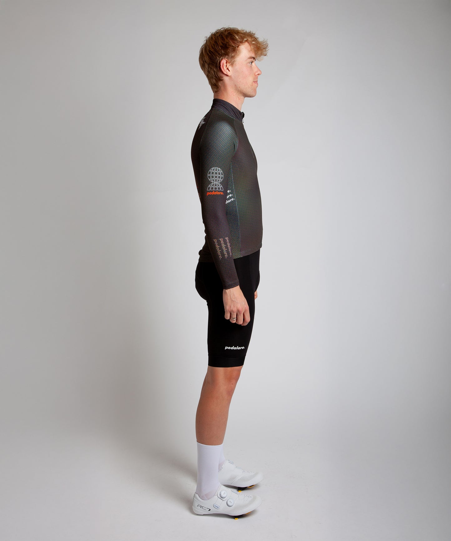 Male cyclist modelling Pedalare’s navy winter long sleeve cycling jersey, paired with black bib shorts. Side profile studio shot highlighting the jersey’s thermal fabric, streamlined fit, and subtle branding. Designed by Perth cycling brand Pedalare for cool-weather performance and style. Men’s winter cycling jersey ideal for road cyclists seeking aero cycling gear and premium cycling apparel.