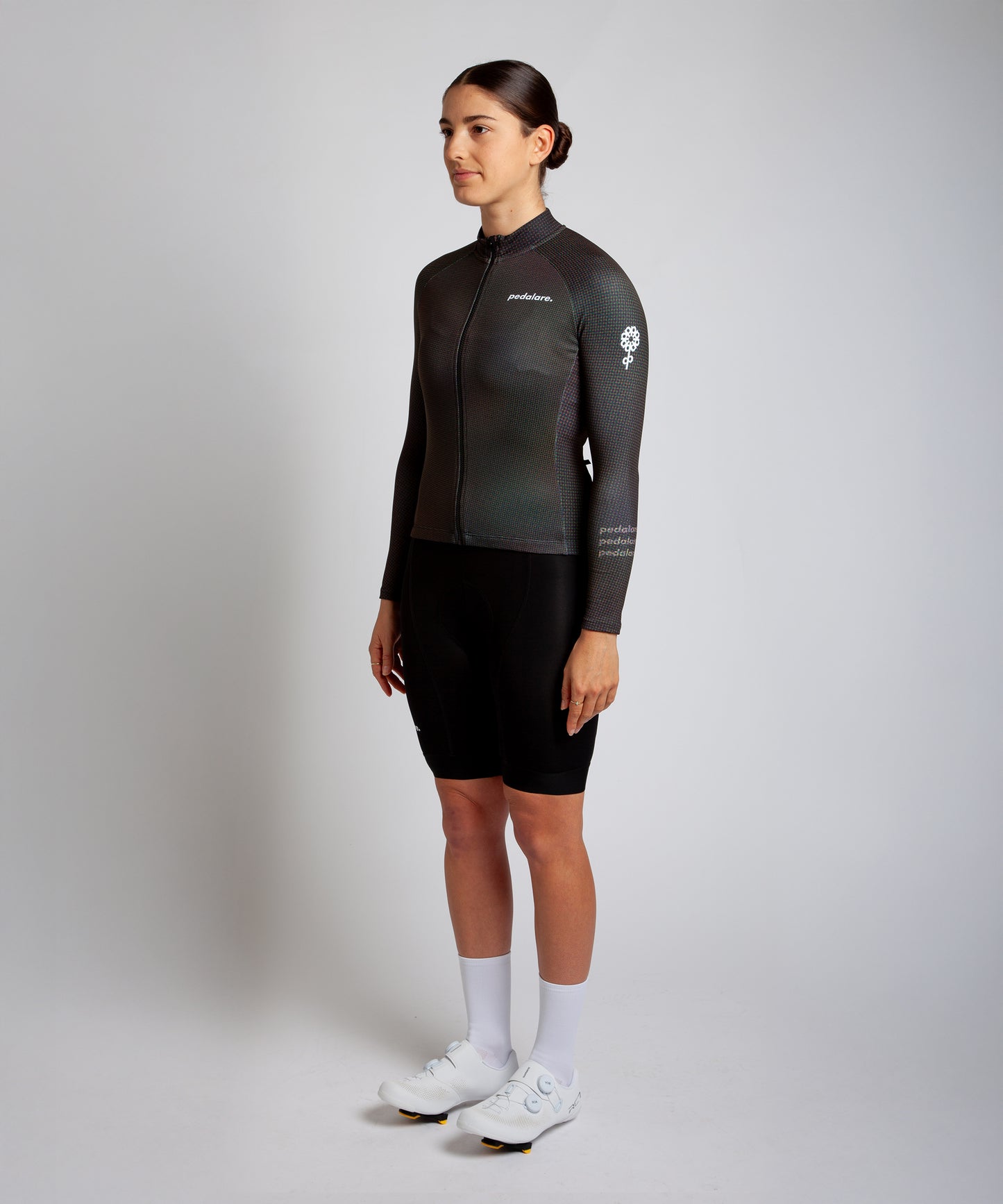 Female cyclist modelling Pedalare’s green winter long sleeve cycling jersey, paired with black bib shorts. Side profile studio shot highlighting the jersey’s thermal fabric, streamlined fit, and subtle branding. Designed by Perth cycling brand Pedalare for cool-weather performance and style. Men’s winter cycling jersey ideal for road cyclists seeking aero cycling gear and premium cycling apparel.
