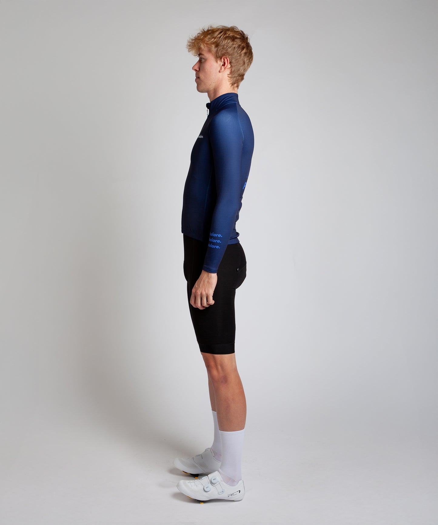 Male cyclist modelling Pedalare’s navy winter long sleeve cycling jersey, paired with black bib shorts. Side profile studio shot highlighting the jersey’s thermal fabric, streamlined fit, and subtle branding. Designed by Perth cycling brand Pedalare for cool-weather performance and style. Men’s winter cycling jersey ideal for road cyclists seeking aero cycling gear and premium cycling apparel.