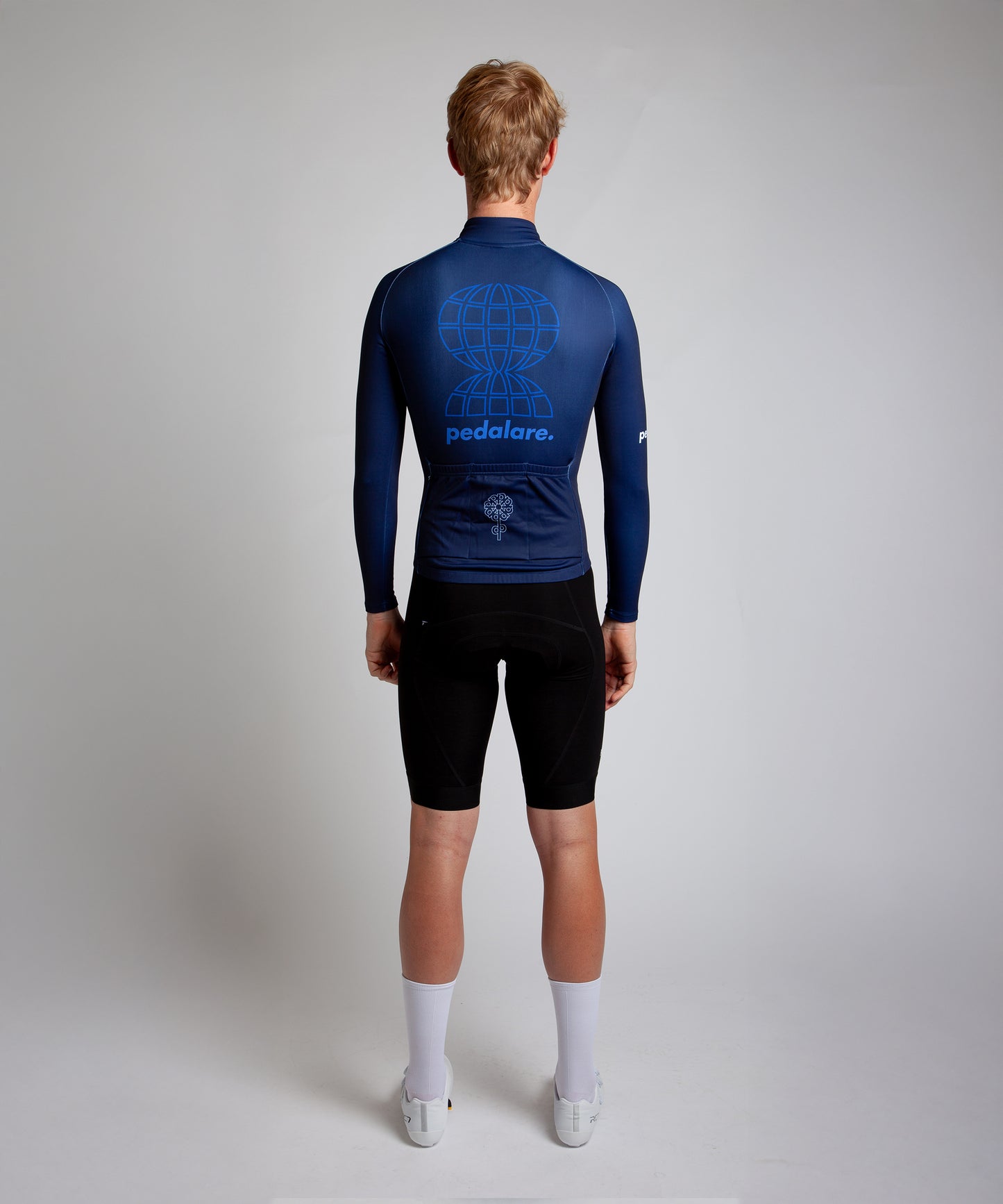 Male cyclist modelling Pedalare’s navy winter long sleeve cycling jersey, paired with black bib shorts. Side profile studio shot highlighting the jersey’s thermal fabric, streamlined fit, and subtle branding. Designed by Perth cycling brand Pedalare for cool-weather performance and style. Men’s winter cycling jersey ideal for road cyclists seeking aero cycling gear and premium cycling apparel.