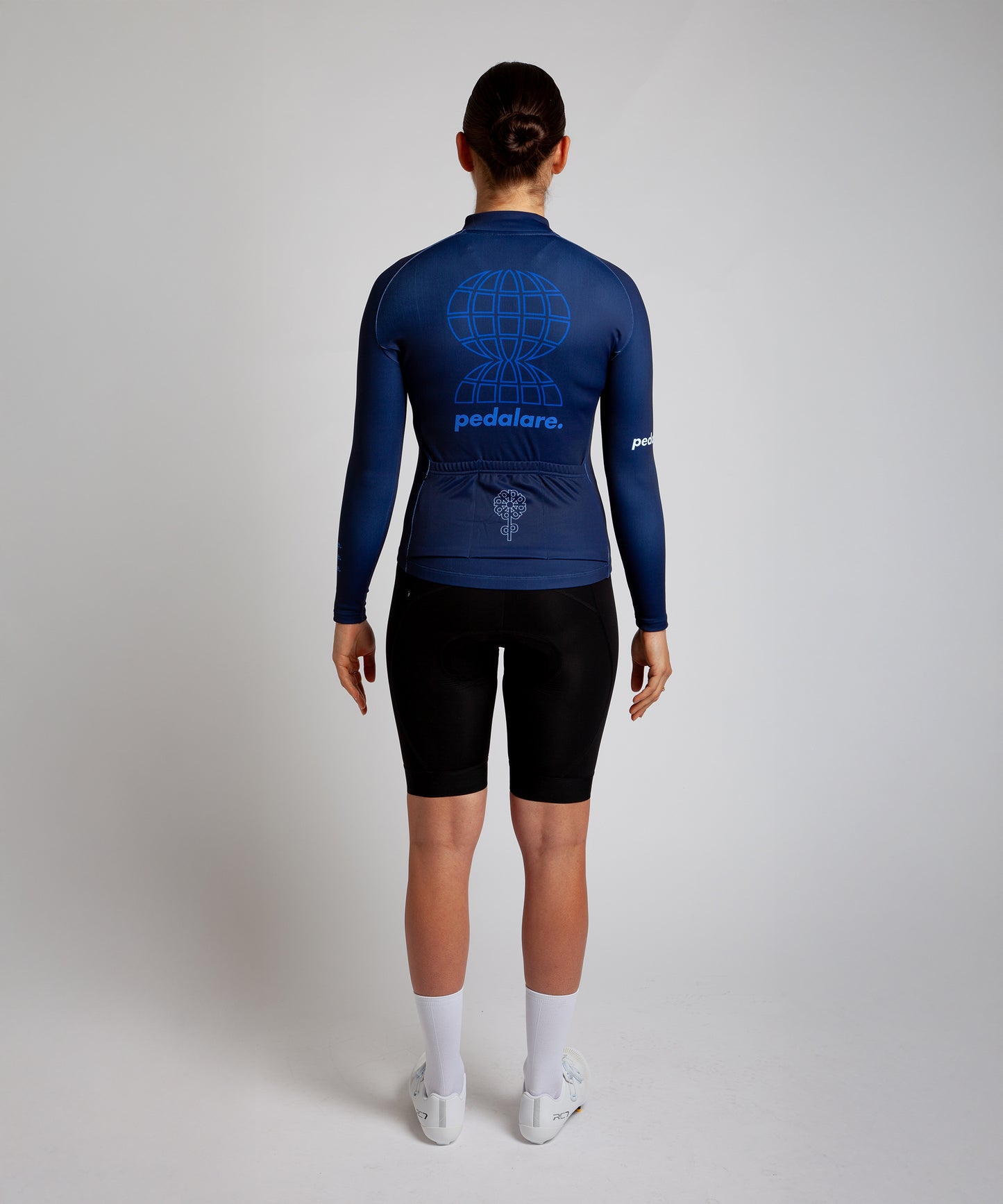 Female cyclist modelling Pedalare’s navy blue winter long sleeve cycling jersey, paired with black bib shorts. Side profile studio shot highlighting the jersey’s thermal fabric, streamlined fit, and subtle branding. Designed by Perth cycling brand Pedalare for cool-weather performance and style. Men’s winter cycling jersey ideal for road cyclists seeking aero cycling gear and premium cycling apparel.
