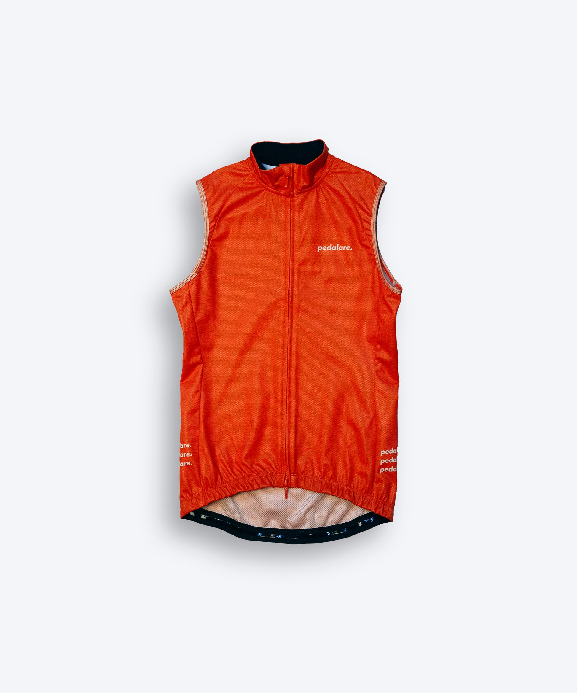Male cyclist wearing Pedalare’s high-performance orange cycling vest, layered over a navy long sleeve jersey and black bib shorts. Side profile studio shot showcasing the vest’s aerodynamic fit and premium detailing. Lightweight, windproof men’s cycling vest ideal for cool weather rides. Designed by Perth cycling brand Pedalare for performance, comfort, and style. Aero cycling gear for dedicated road cyclists.