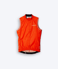 Female cyclist wearing Pedalare’s high-performance orange cycling vest, layered over a navy long sleeve jersey and black bib shorts. Side profile studio shot showcasing the vest’s aerodynamic fit and premium detailing. Lightweight, windproof men’s cycling vest ideal for cool weather rides. Designed by Perth cycling brand Pedalare for performance, comfort, and style. Aero cycling gear for dedicated road cyclists.