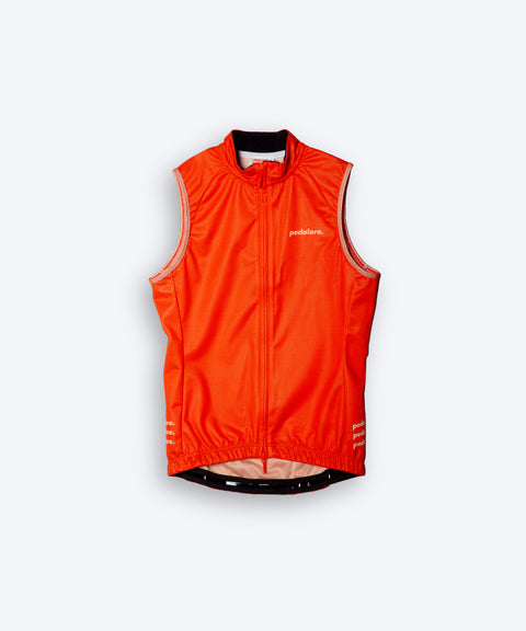 Female cyclist wearing Pedalare’s high-performance orange cycling vest, layered over a navy long sleeve jersey and black bib shorts. Side profile studio shot showcasing the vest’s aerodynamic fit and premium detailing. Lightweight, windproof men’s cycling vest ideal for cool weather rides. Designed by Perth cycling brand Pedalare for performance, comfort, and style. Aero cycling gear for dedicated road cyclists.