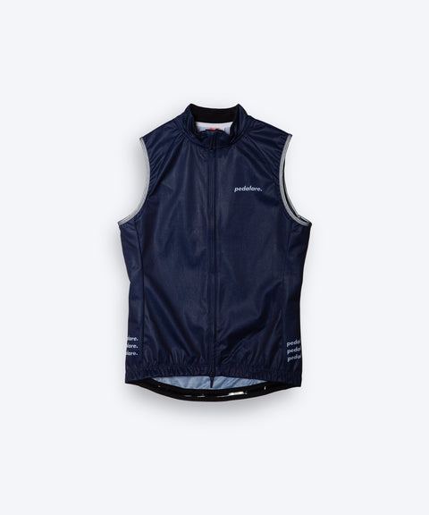 Female cyclist wearing Pedalare’s high-performance navy, blue cycling vest, layered over a navy long sleeve jersey and black bib shorts. Side profile studio shot showcasing the vest’s aerodynamic fit and premium detailing. Lightweight, windproof men’s cycling vest ideal for cool weather rides. Designed by Perth cycling brand Pedalare for performance, comfort, and style. Aero cycling gear for dedicated road cyclists.
