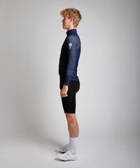 Male men’s cyclist wearing Pedalare’s high-performance navy, blue cycling vest, layered over a navy long sleeve jersey and black bib shorts. Side profile studio shot showcasing the vest’s aerodynamic fit and premium detailing. Lightweight, windproof men’s cycling vest ideal for cool weather rides. Designed by Perth cycling brand Pedalare for performance, comfort, and style. Aero cycling gear for dedicated road cyclists.