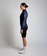 Female cyclist wearing Pedalare’s high-performance navy, blue cycling vest, layered over a navy long sleeve jersey and black bib shorts. Side profile studio shot showcasing the vest’s aerodynamic fit and premium detailing. Lightweight, windproof men’s cycling vest ideal for cool weather rides. Designed by Perth cycling brand Pedalare for performance, comfort, and style. Aero cycling gear for dedicated road cyclists.