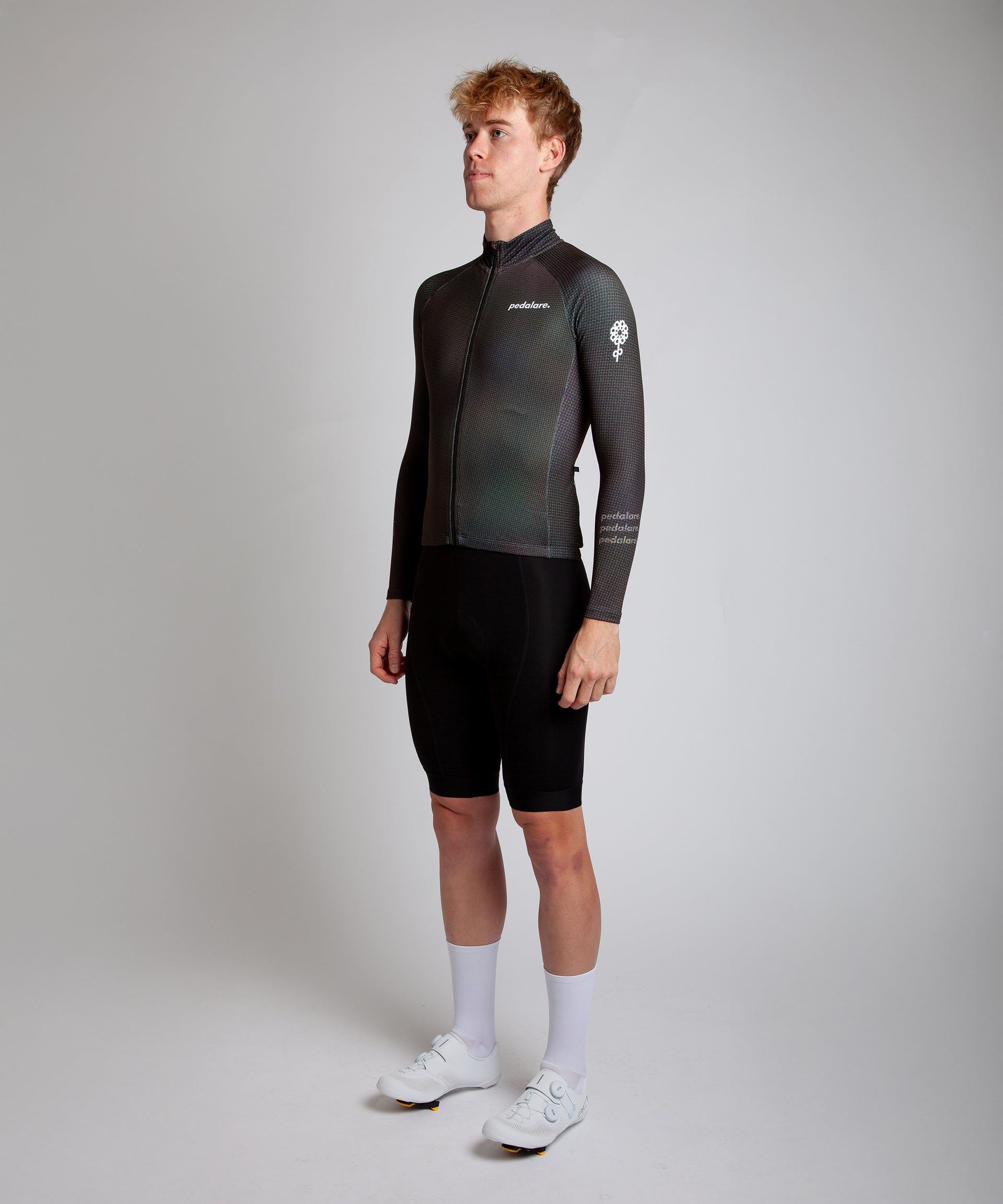 Male cyclist modelling Pedalare’s navy winter long sleeve cycling jersey, paired with black bib shorts. Side profile studio shot highlighting the jersey’s thermal fabric, streamlined fit, and subtle branding. Designed by Perth cycling brand Pedalare for cool-weather performance and style. Men’s winter cycling jersey ideal for road cyclists seeking aero cycling gear and premium cycling apparel.