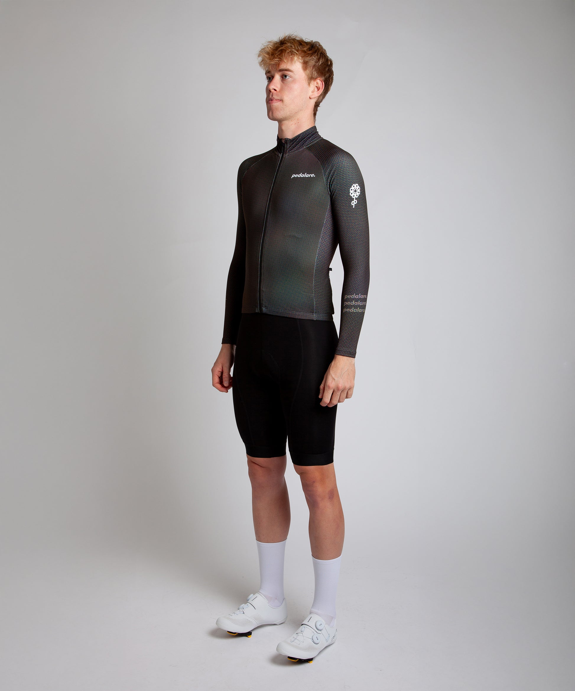 Male cyclist modelling Pedalare’s navy winter long sleeve cycling jersey, paired with black bib shorts. Side profile studio shot highlighting the jersey’s thermal fabric, streamlined fit, and subtle branding. Designed by Perth cycling brand Pedalare for cool-weather performance and style. Men’s winter cycling jersey ideal for road cyclists seeking aero cycling gear and premium cycling apparel.