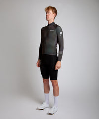 Male cyclist modelling Pedalare’s navy winter long sleeve cycling jersey, paired with black bib shorts. Side profile studio shot highlighting the jersey’s thermal fabric, streamlined fit, and subtle branding. Designed by Perth cycling brand Pedalare for cool-weather performance and style. Men’s winter cycling jersey ideal for road cyclists seeking aero cycling gear and premium cycling apparel.