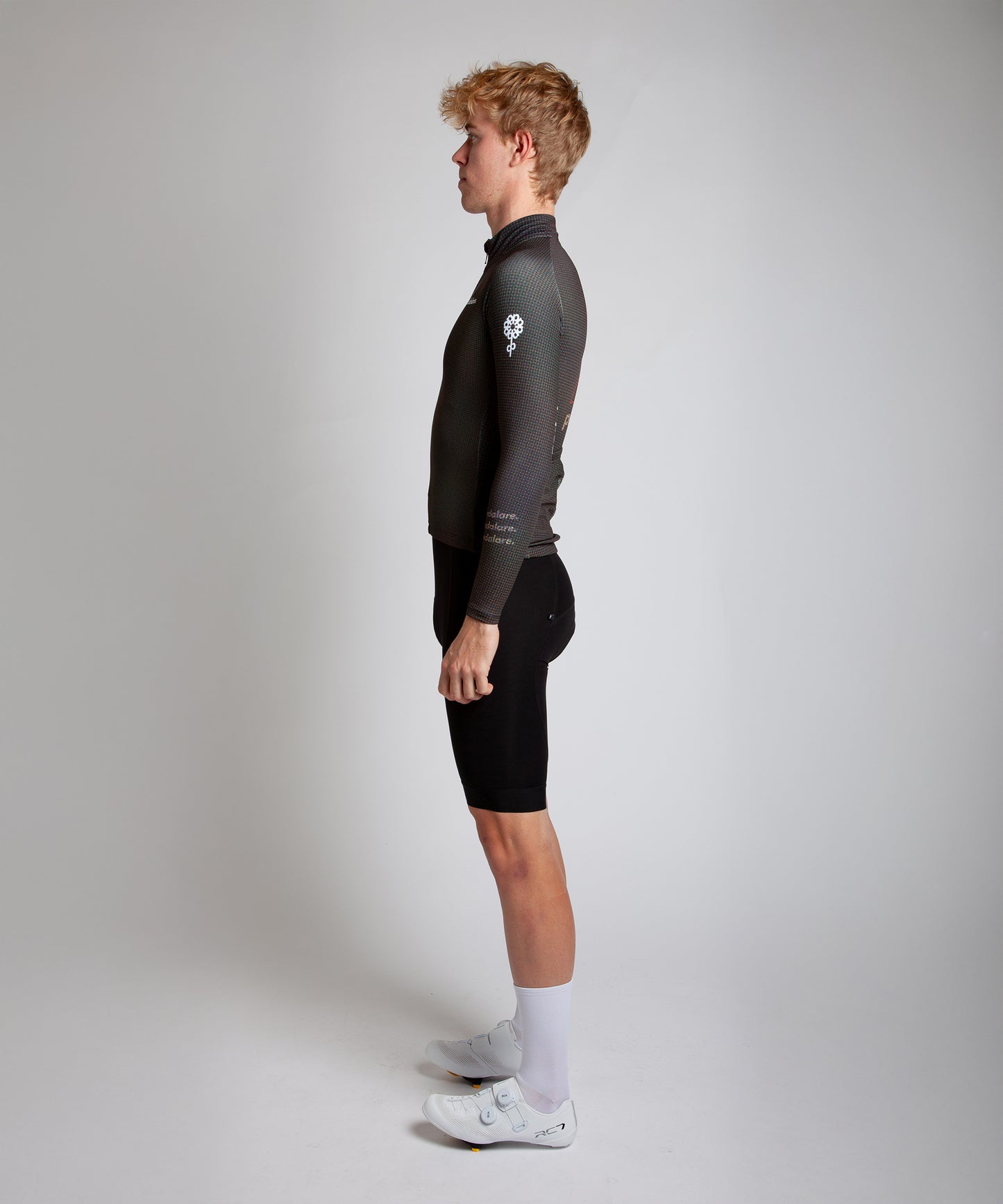 Male cyclist modelling Pedalare’s navy winter long sleeve cycling jersey, paired with black bib shorts. Side profile studio shot highlighting the jersey’s thermal fabric, streamlined fit, and subtle branding. Designed by Perth cycling brand Pedalare for cool-weather performance and style. Men’s winter cycling jersey ideal for road cyclists seeking aero cycling gear and premium cycling apparel.
