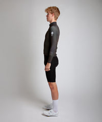 Male cyclist modelling Pedalare’s navy winter long sleeve cycling jersey, paired with black bib shorts. Side profile studio shot highlighting the jersey’s thermal fabric, streamlined fit, and subtle branding. Designed by Perth cycling brand Pedalare for cool-weather performance and style. Men’s winter cycling jersey ideal for road cyclists seeking aero cycling gear and premium cycling apparel.