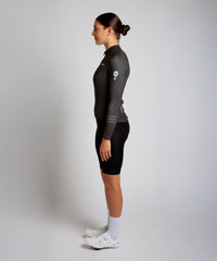 Female cyclist modelling Pedalare’s green winter long sleeve cycling jersey, paired with black bib shorts. Side profile studio shot highlighting the jersey’s thermal fabric, streamlined fit, and subtle branding. Designed by Perth cycling brand Pedalare for cool-weather performance and style. Men’s winter cycling jersey ideal for road cyclists seeking aero cycling gear and premium cycling apparel.