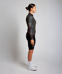 Female cyclist modelling Pedalare’s green winter long sleeve cycling jersey, paired with black bib shorts. Side profile studio shot highlighting the jersey’s thermal fabric, streamlined fit, and subtle branding. Designed by Perth cycling brand Pedalare for cool-weather performance and style. Men’s winter cycling jersey ideal for road cyclists seeking aero cycling gear and premium cycling apparel.
